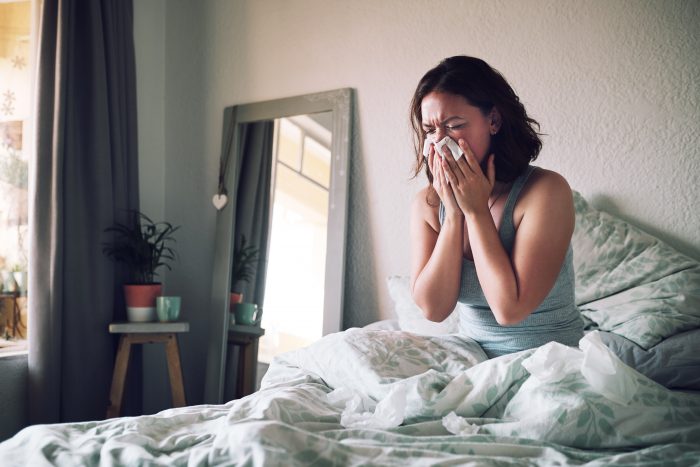 A lady with allergies struggling to get out of bed